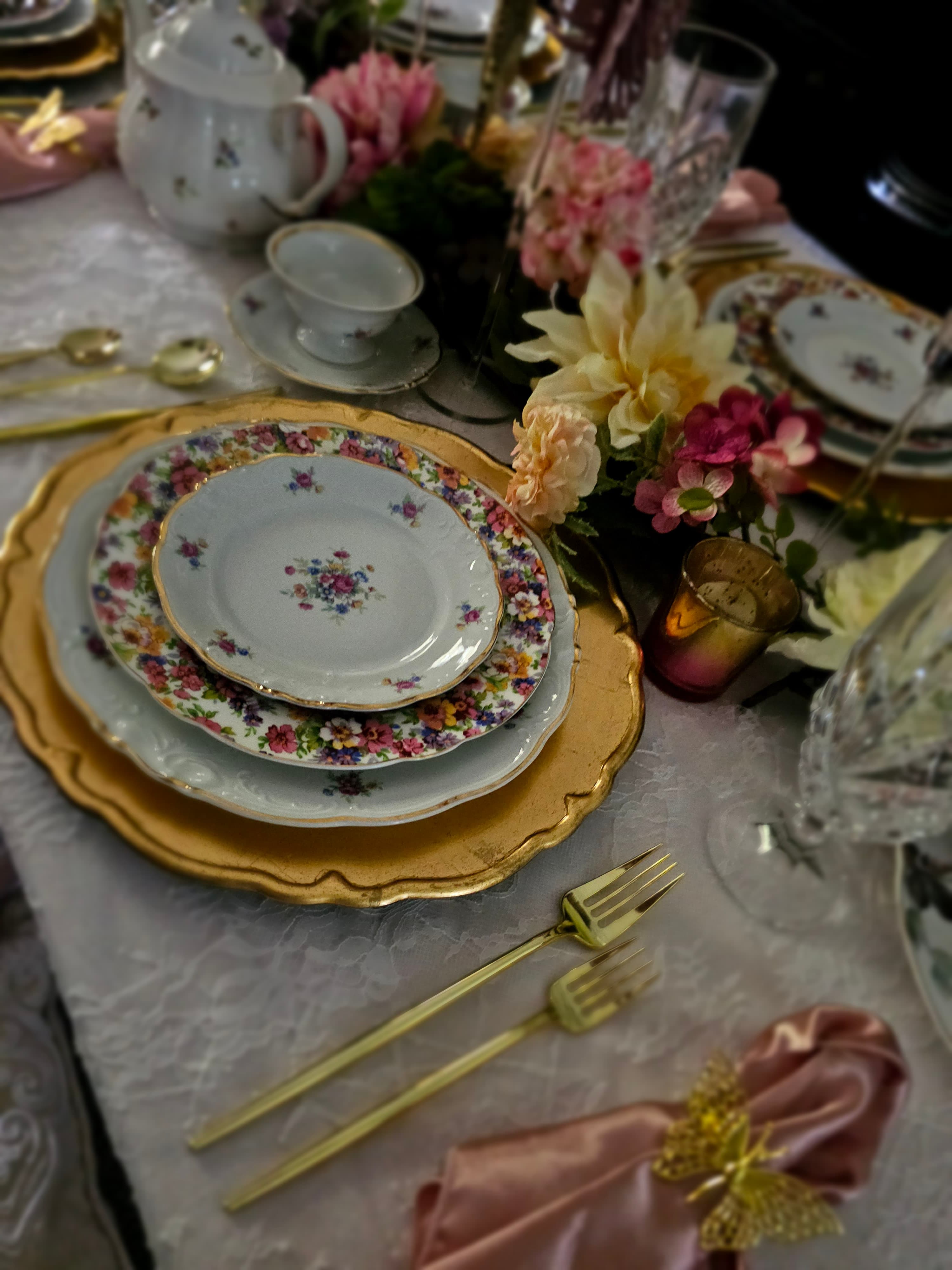 A vintage china table setting with gold flatware and florals