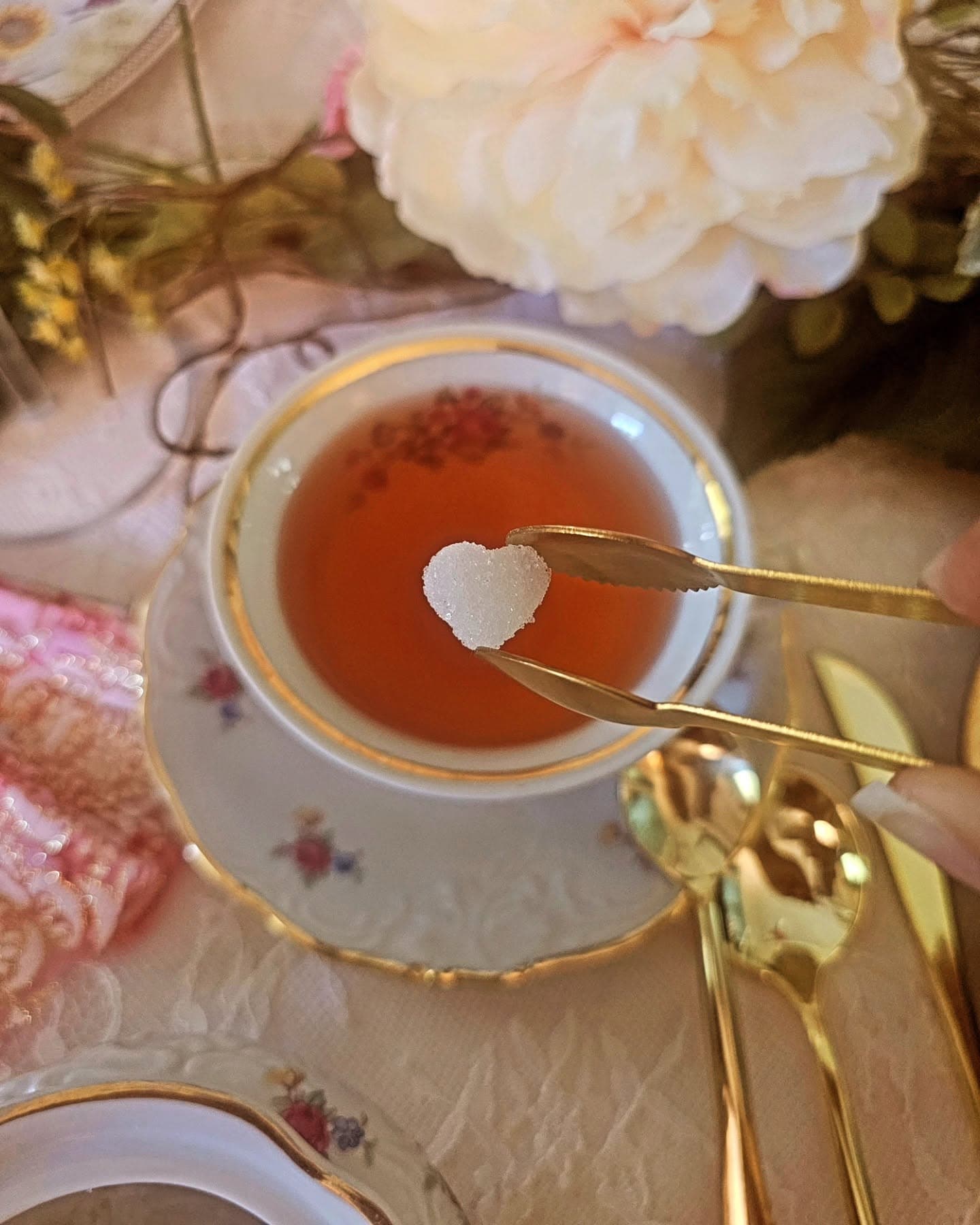 A heart-shaped sugar cube being added to a cup of tea