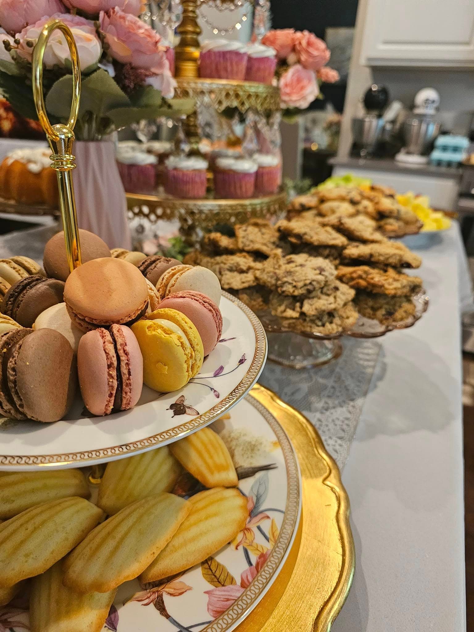 A tiered tea party dessert display with macarons, cupcakes, and cookies by Something Sweet LLC